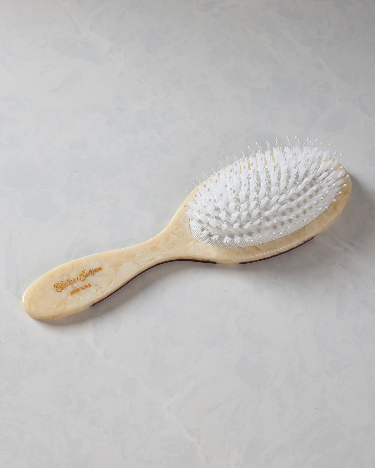 Full view of a brown-and-cream hand-painted hair brush with white bristles and a curved handle.