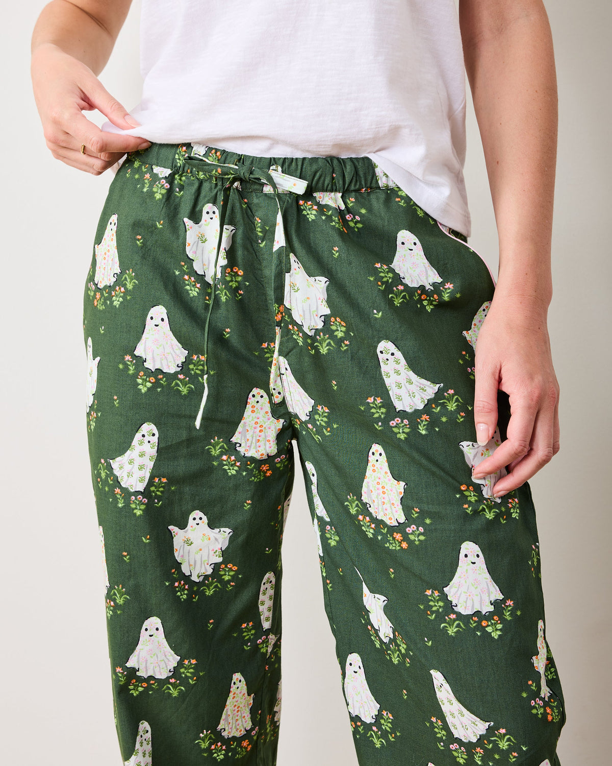 Front detail of Gardening Ghosts pajama pants showing the drawstring waistband, side pockets, and ghost-and-flower print.