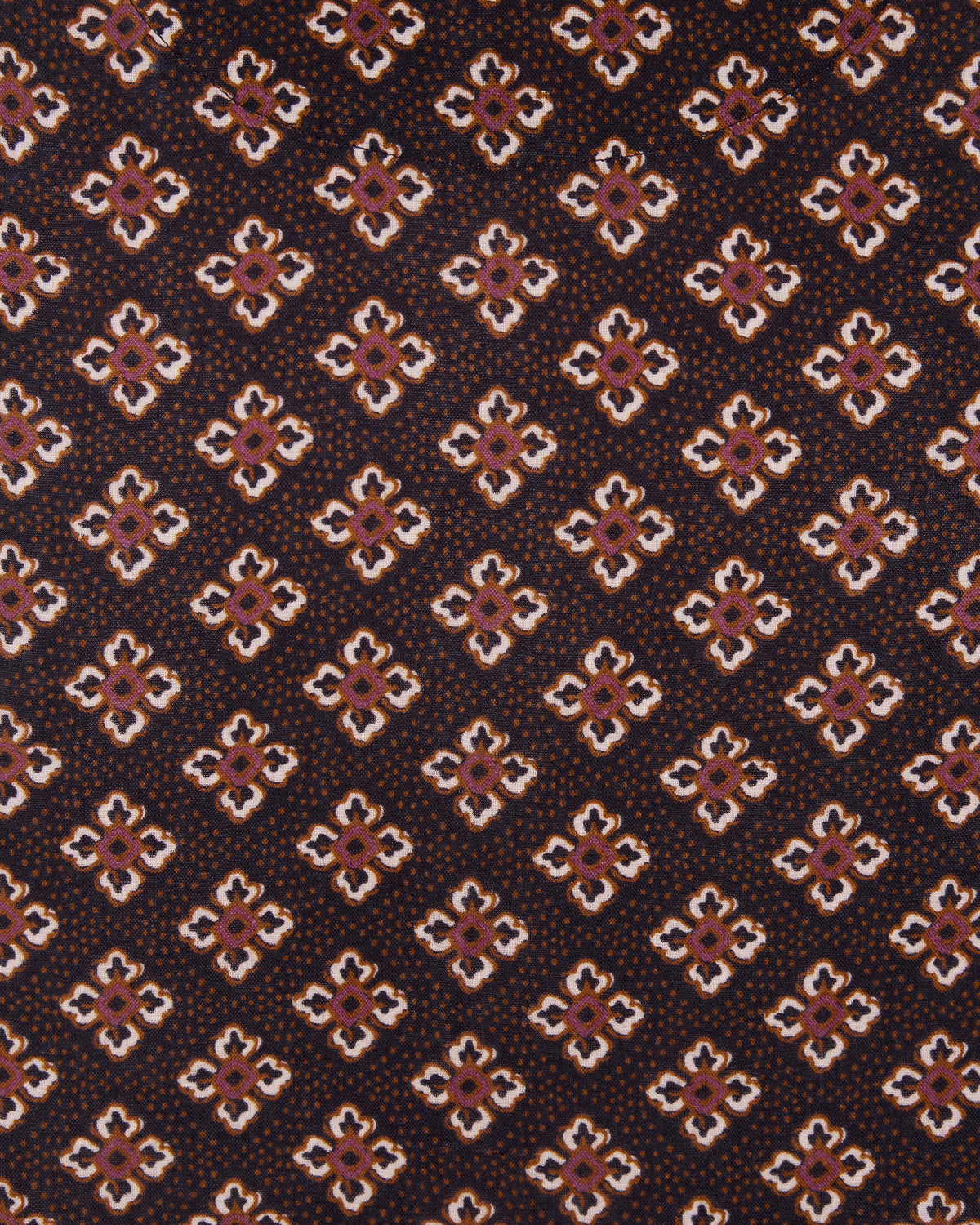 Close-up of dark brown fabric with repeating small geometric floral motifs in white, pink, and brown.
