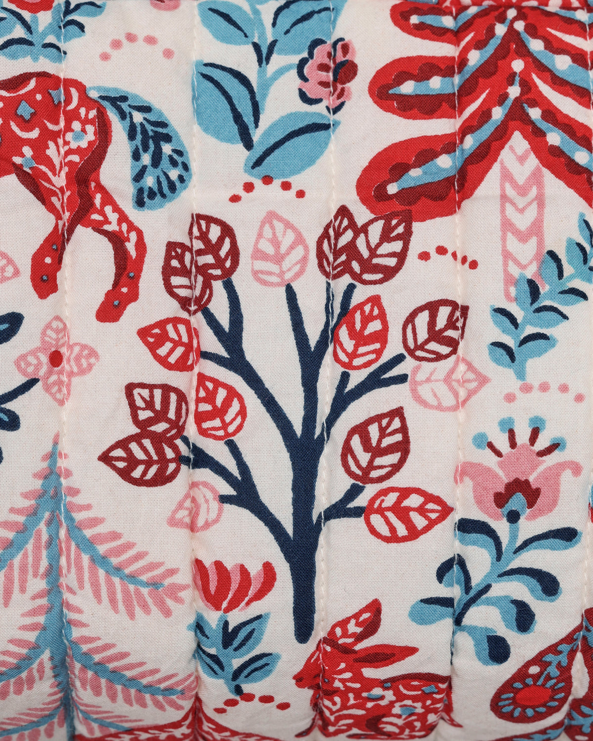 Close-up of a cream-colored illustrated pattern with stylized leaves, flowers, and red and blue decorative motifs.