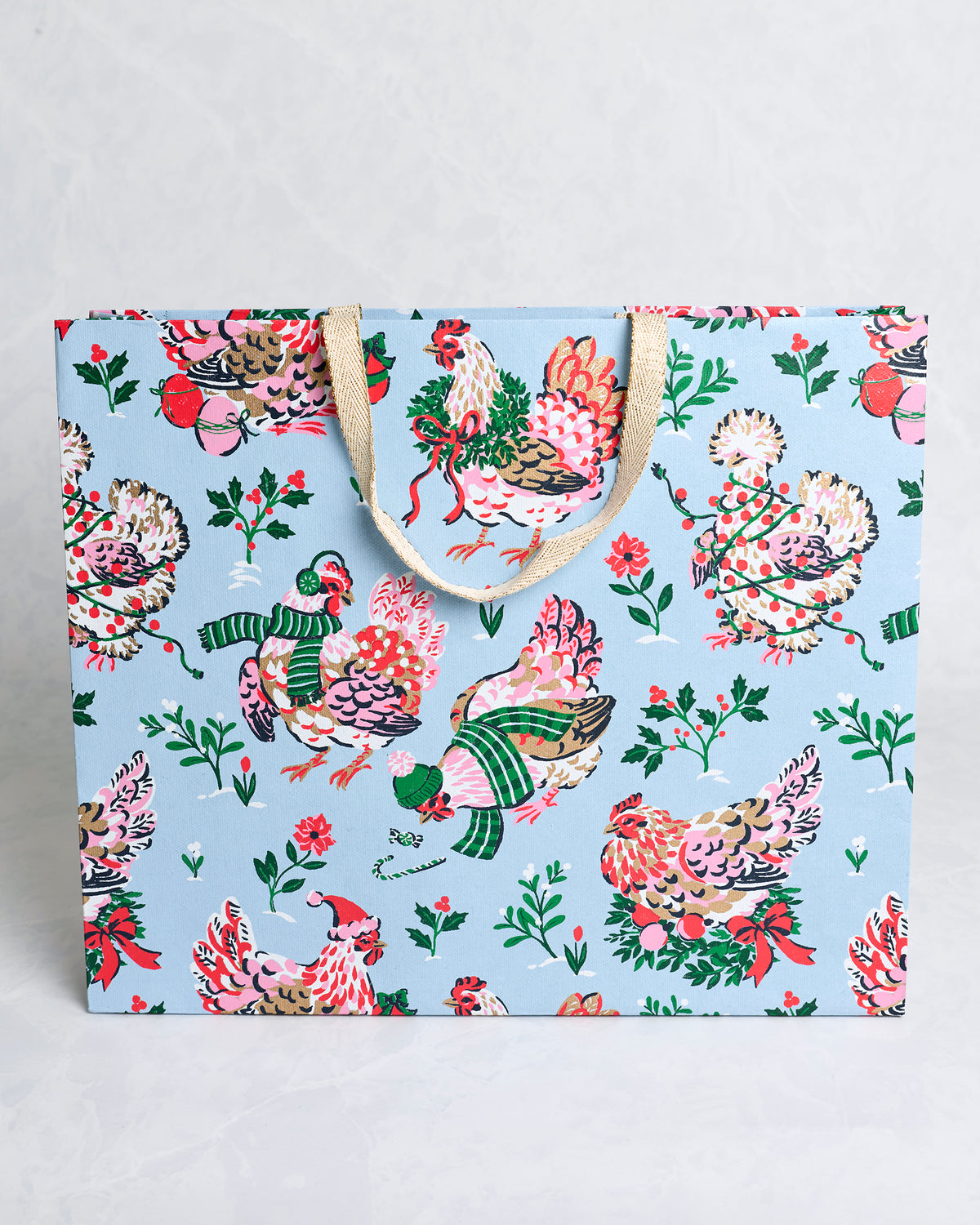 Front view of the Holiday Hens pale blue handmade gift bag with decorated hens, holly branches, berries, and tan handles.