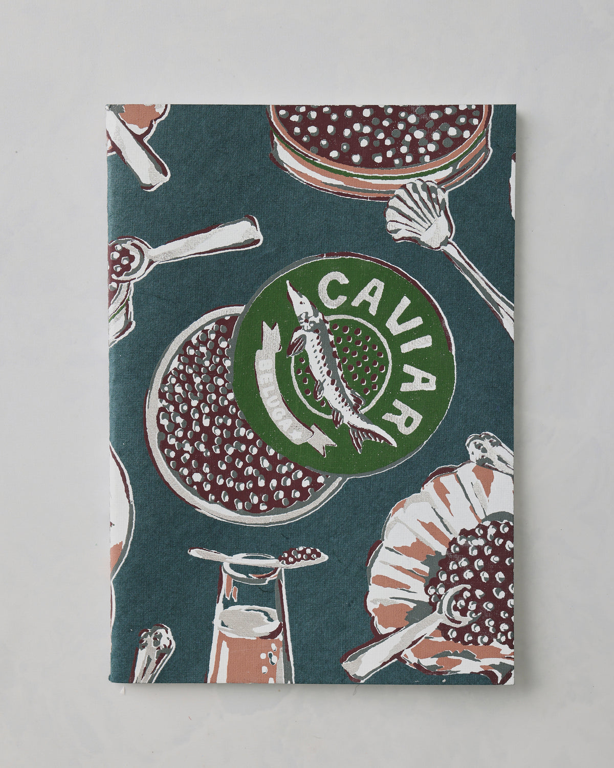 Dark teal Champagne and Caviar notebook cover with illustrations of caviar dishes, serving utensils, and the word “CAVIAR.”
