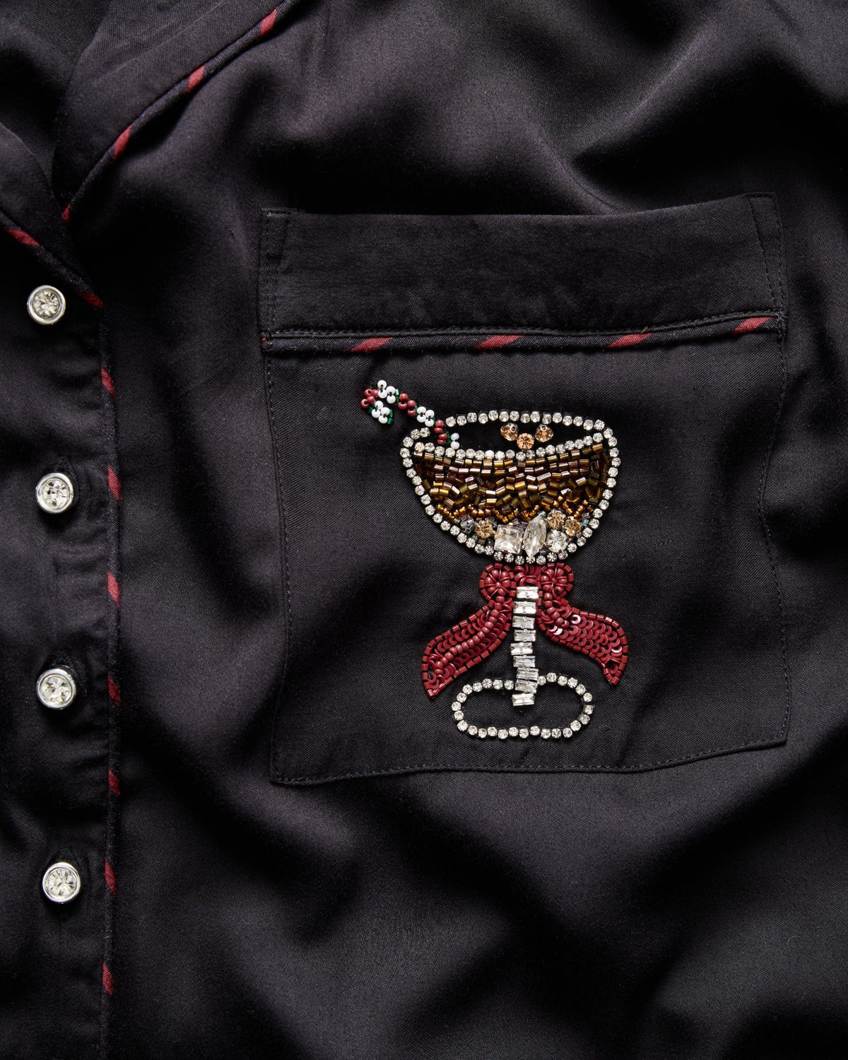 Close-up of the black shirt chest pocket with martini-glass bead embroidery and red-trimmed pocket piping.