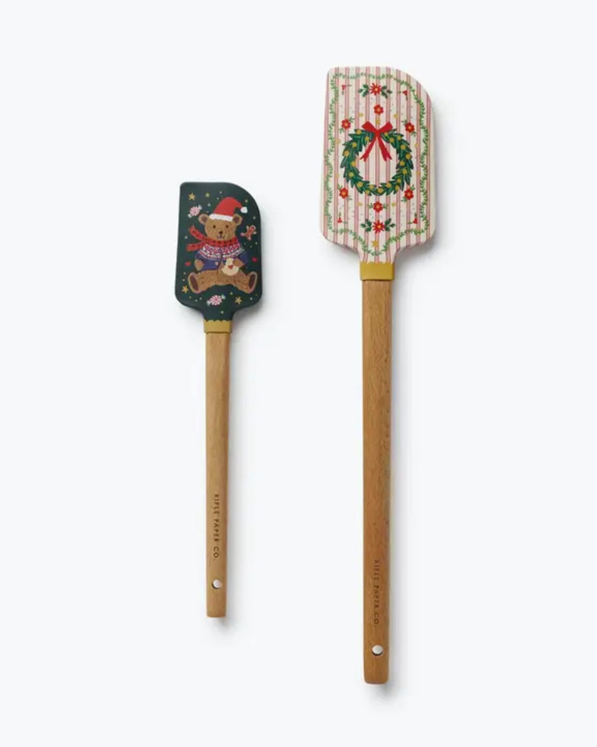 Set of two holiday spatulas with wooden handles, featuring a teddy bear design on the small spatula and a wreath design on the large spatula.