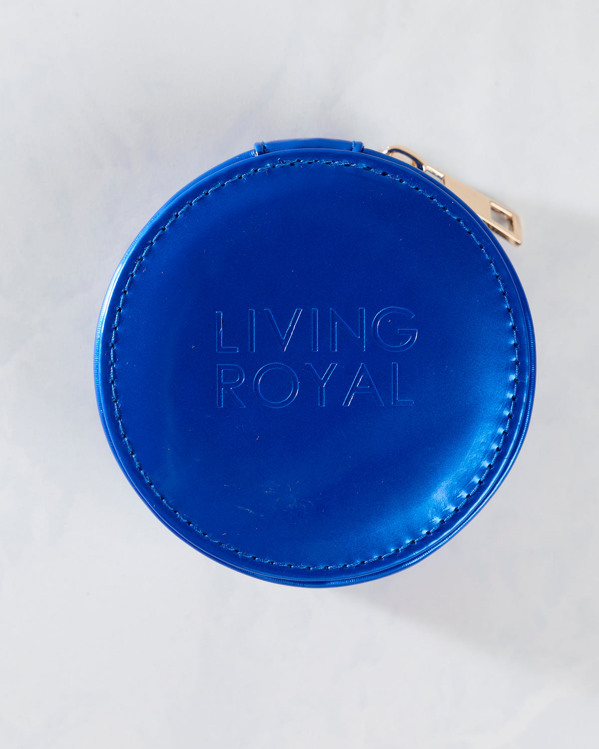 Back of the blue round pill case embossed with the words LIVING ROYAL.