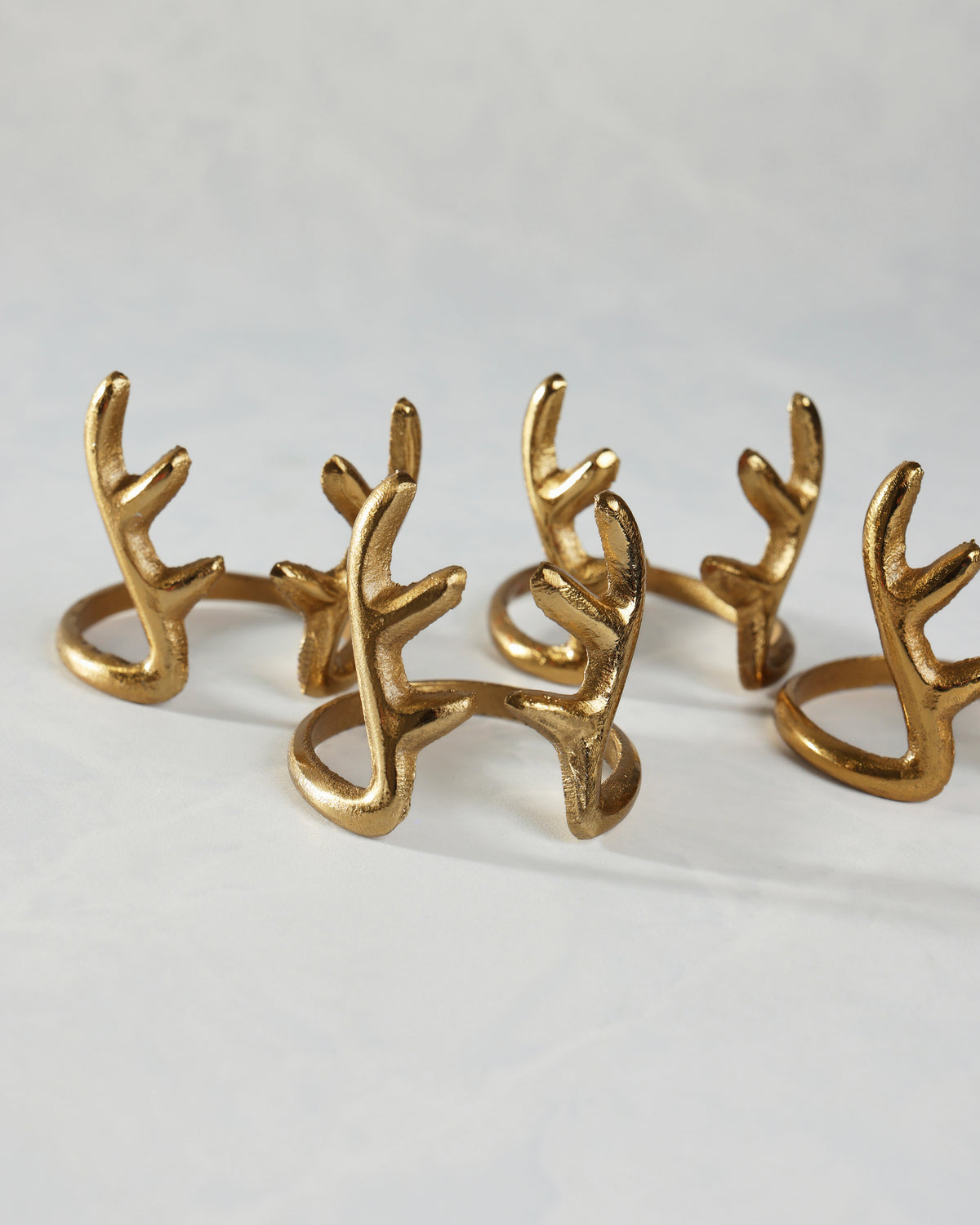 Several gold antlers napkin rings arranged on a white surface.