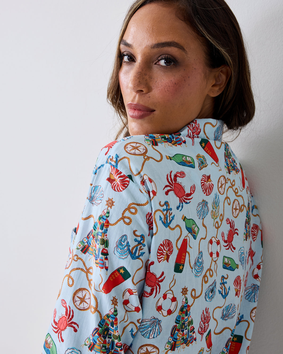 Close-up of the back and shoulder of a light blue pajama top with a nautical Christmas print.