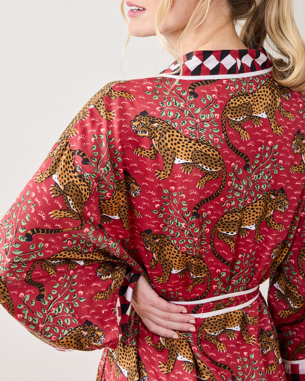 Back view of a person wearing the scarlet Bagheera robe, showing the leopard print, leafy pattern, white piping, and geometric collar trim.