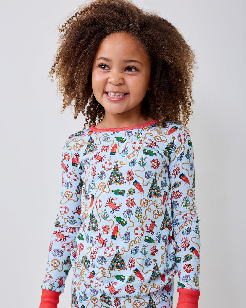 Child wearing the light blue long-sleeve pajama top with a nautical Christmas print and red cuffs.