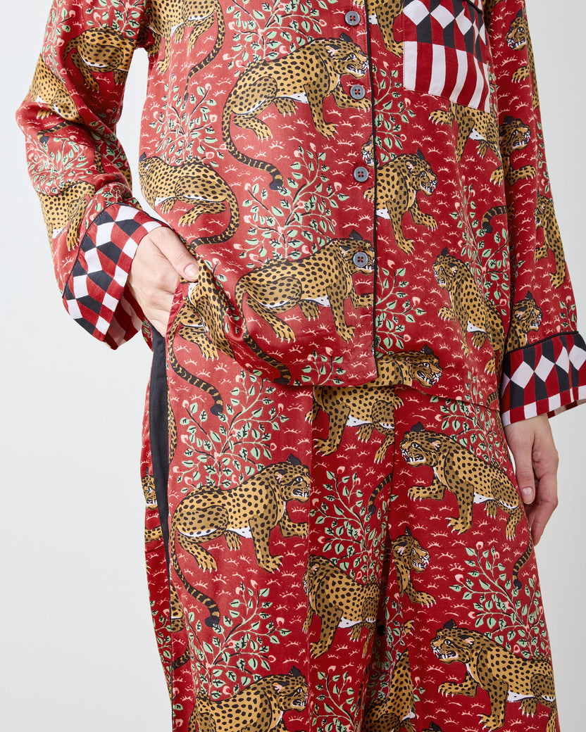 Close-up of the red leopard-print pajama shirt and pants showing buttons, chest pocket, cuffs, and side pockets.