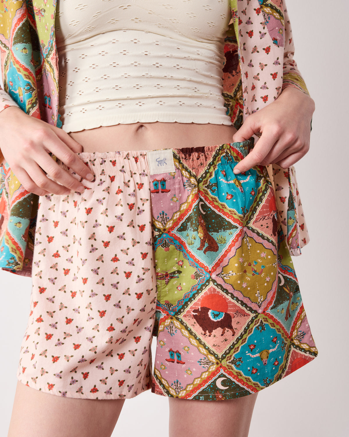 Close-up of the Western Scenes pajama set showing a long-sleeve top and matching shorts with patchwork western-print panels.