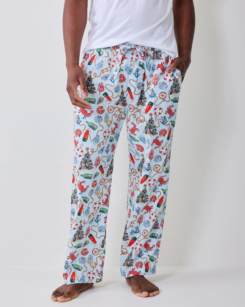 Front view of the men's long pajama pants with a light blue nautical holiday print and side pockets.