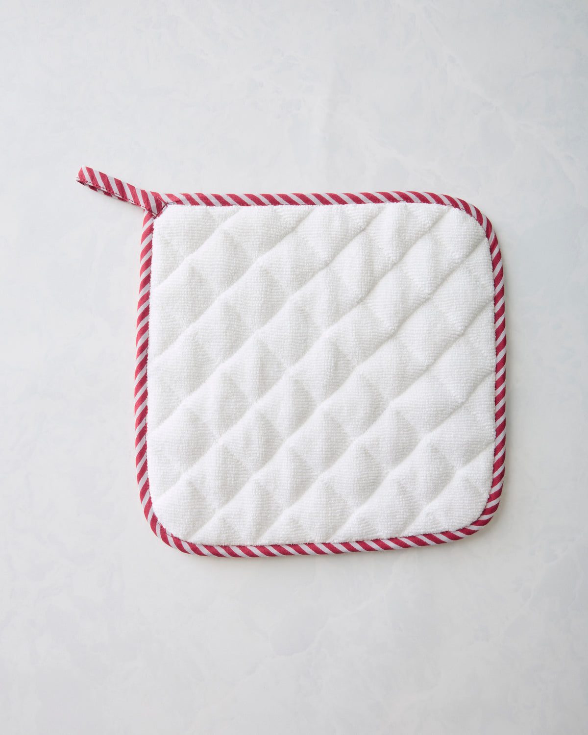 Back of the pot holder showing a white quilted surface with red-and-white striped edging.