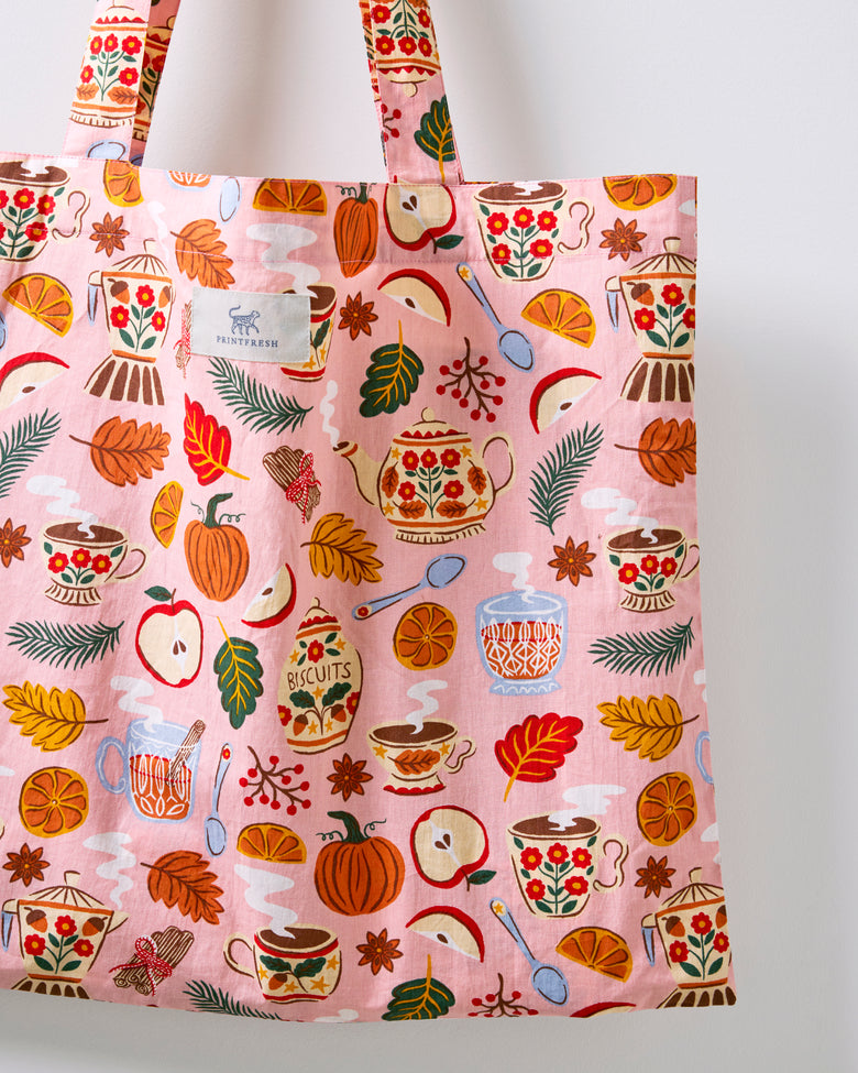 Close-up of the rose pink tea-themed tote bag showing its printed fabric and brand label.