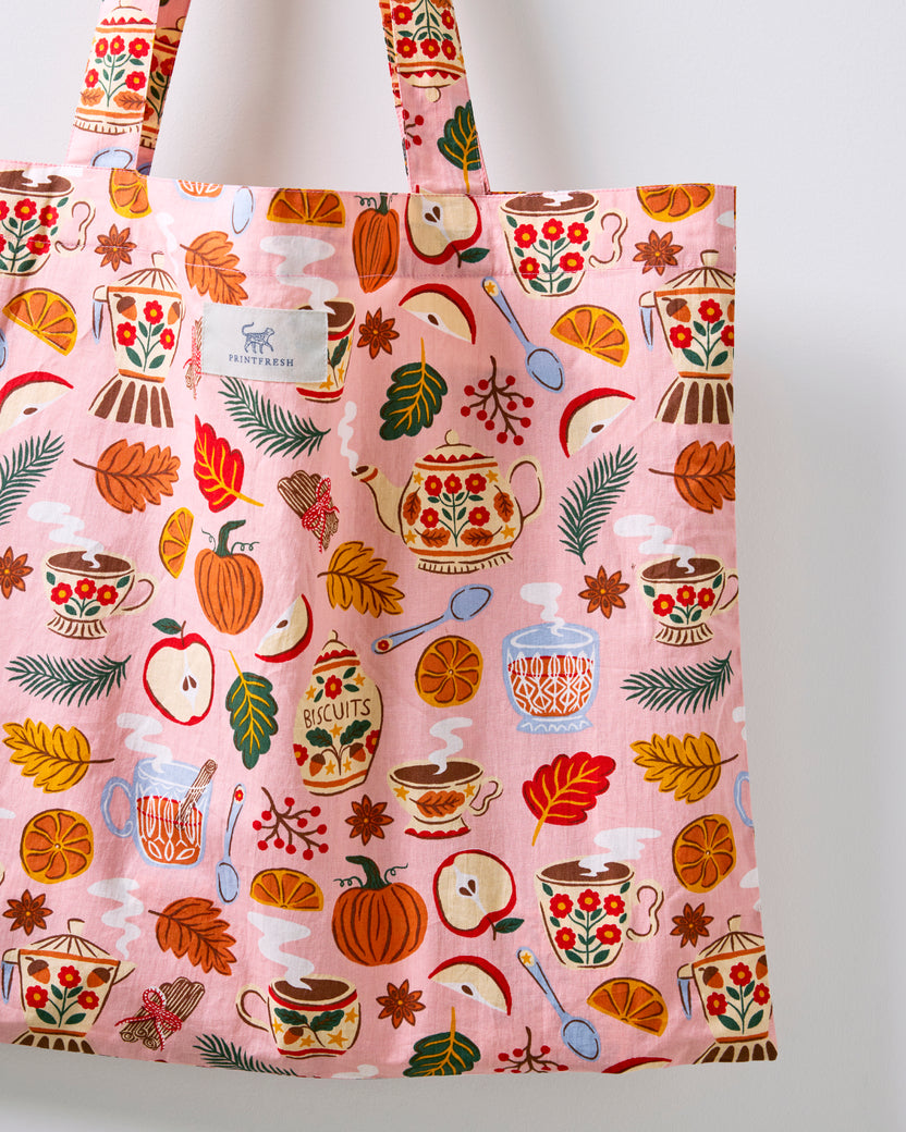 Close-up of the rose pink tea-themed tote bag showing its printed fabric and brand label.