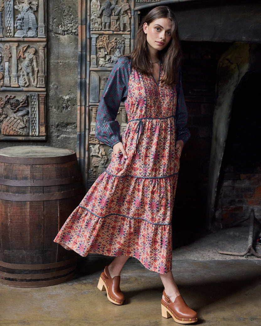 Angled view of the Winged Tapestry Eden Dress showing the flowing tiered skirt, floral print, and blue patterned sleeves.