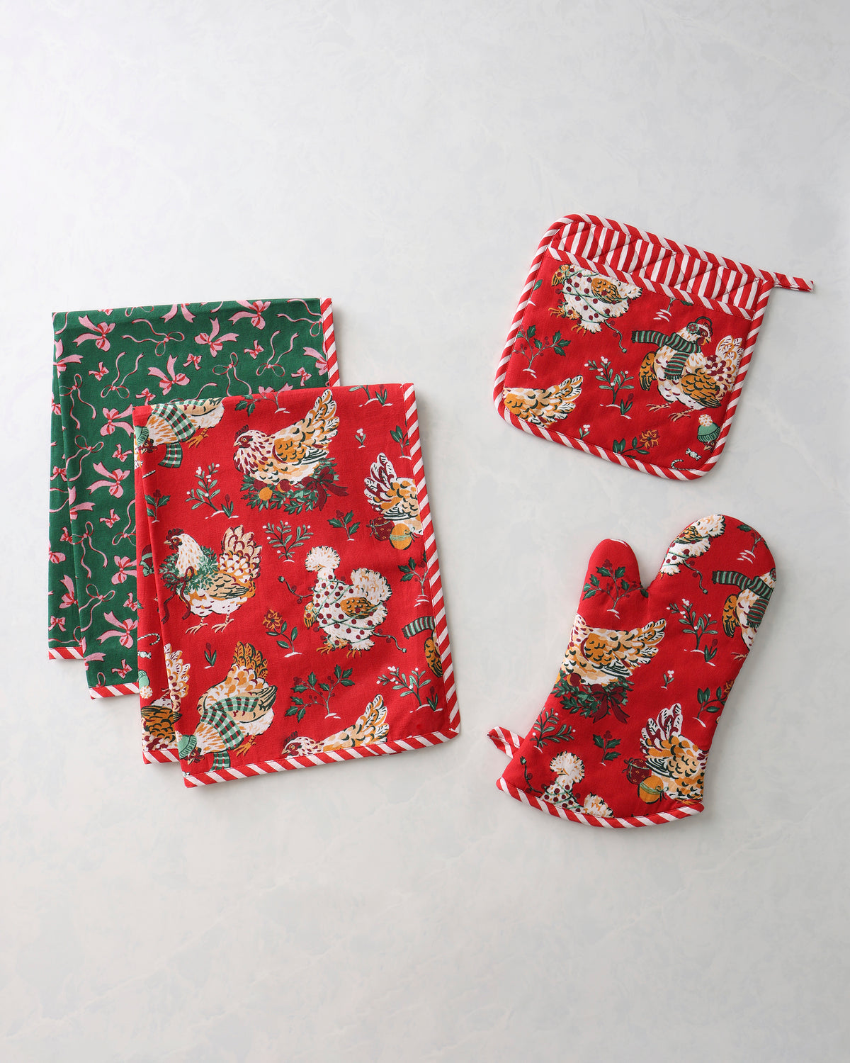 Holiday Hens kitchen bundle with two red patterned tea towels, one green patterned tea towel, an oven mitt, and a pot holder
