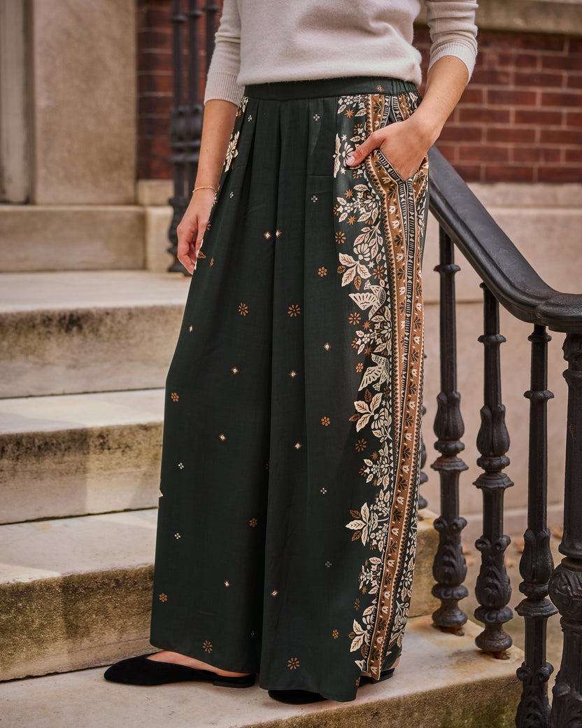 Spruce Sasha wide-leg pants with a floral tapestry print and contrasting patterned side border, shown on a model standing on steps.