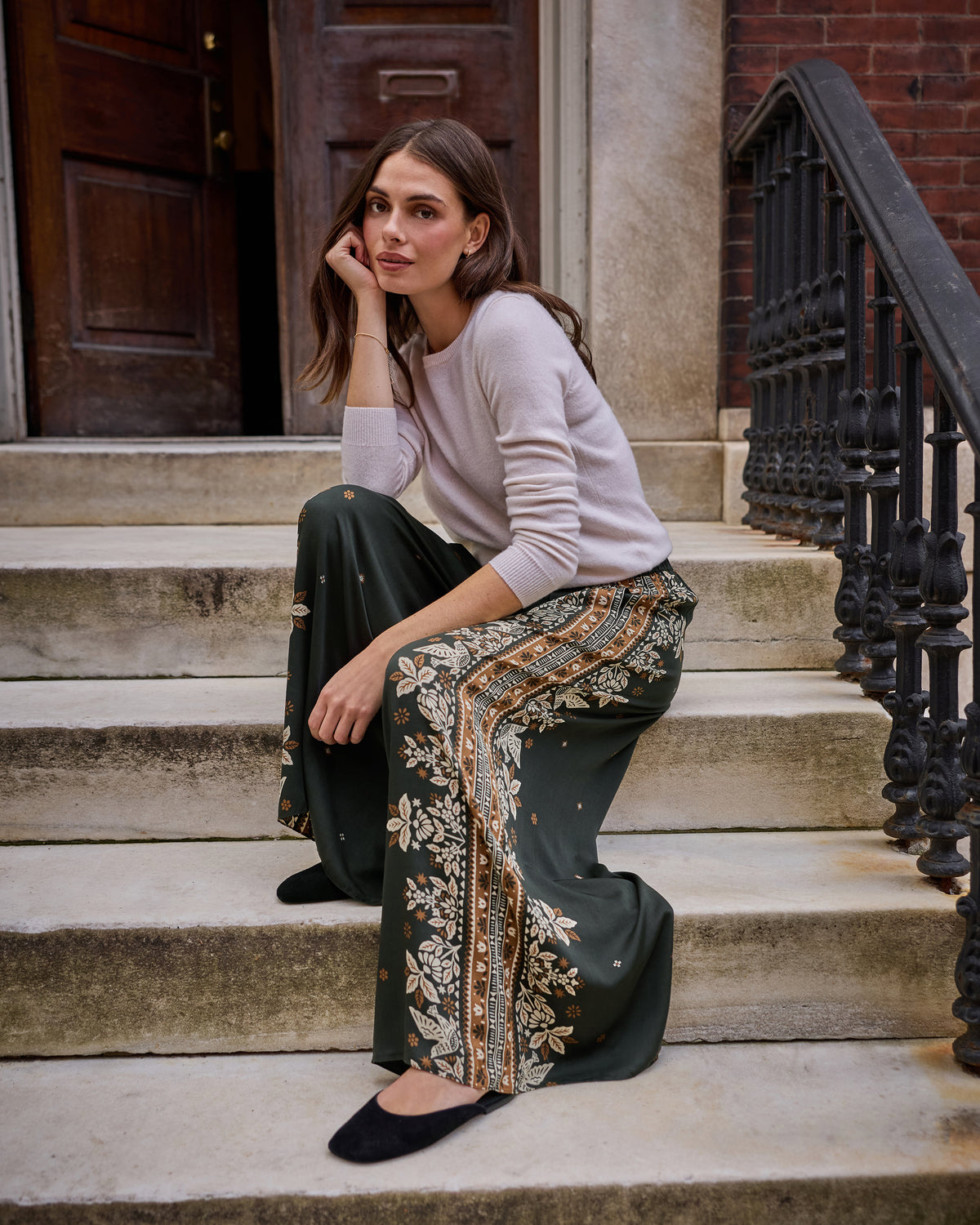 Spruce Sasha pants with a floral tapestry print and contrasting side border, shown on a seated model.