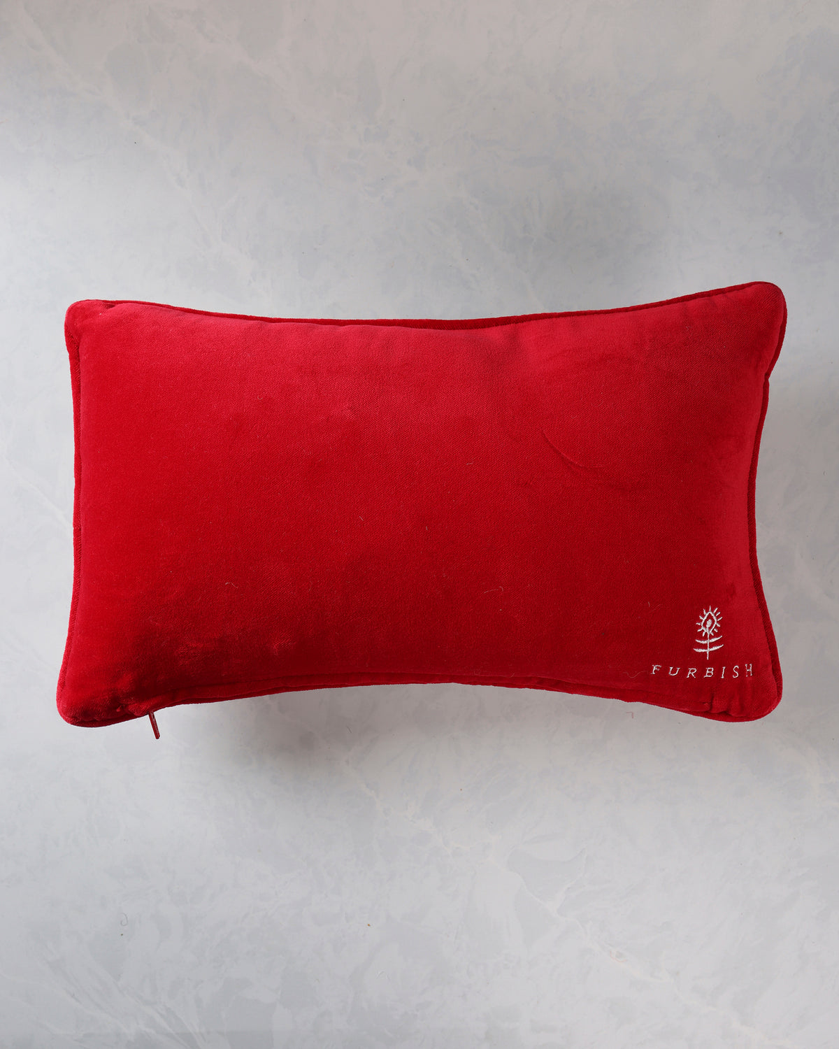 Back of the red pillow with a white Furbish logo near the lower right corner.