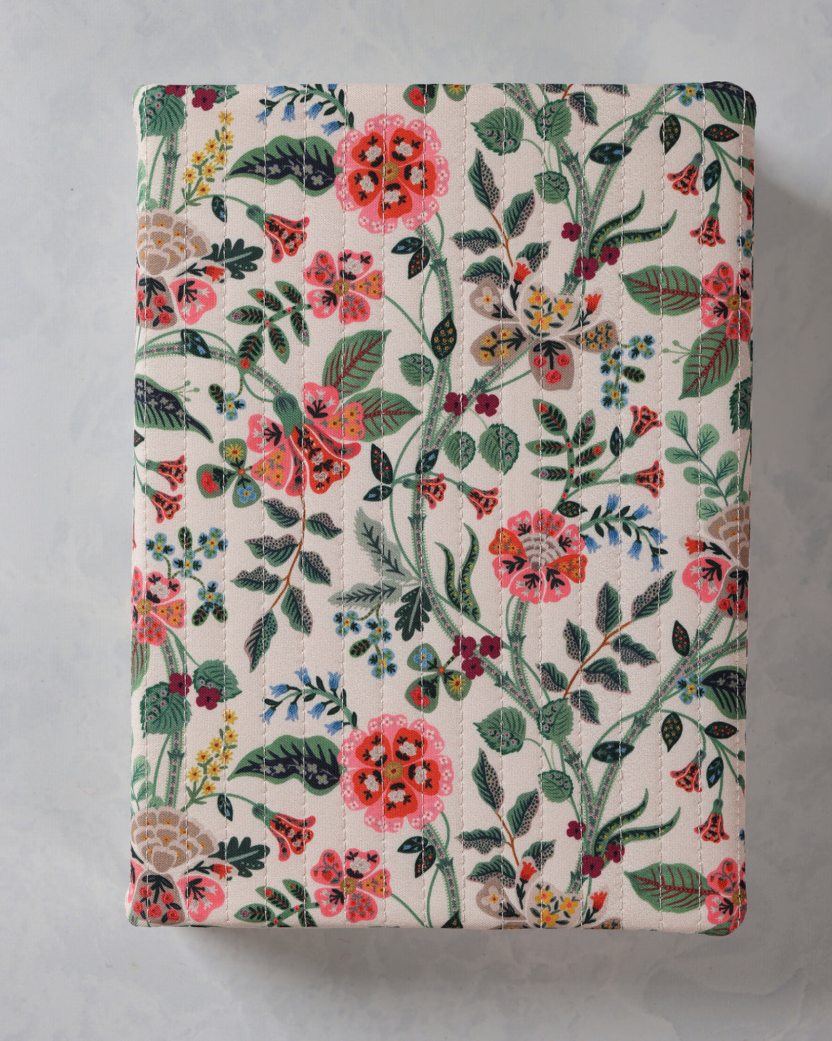Closed hardbound journal with a quilted floral cover featuring pink, red, blue, green, and yellow flowers and leaves.