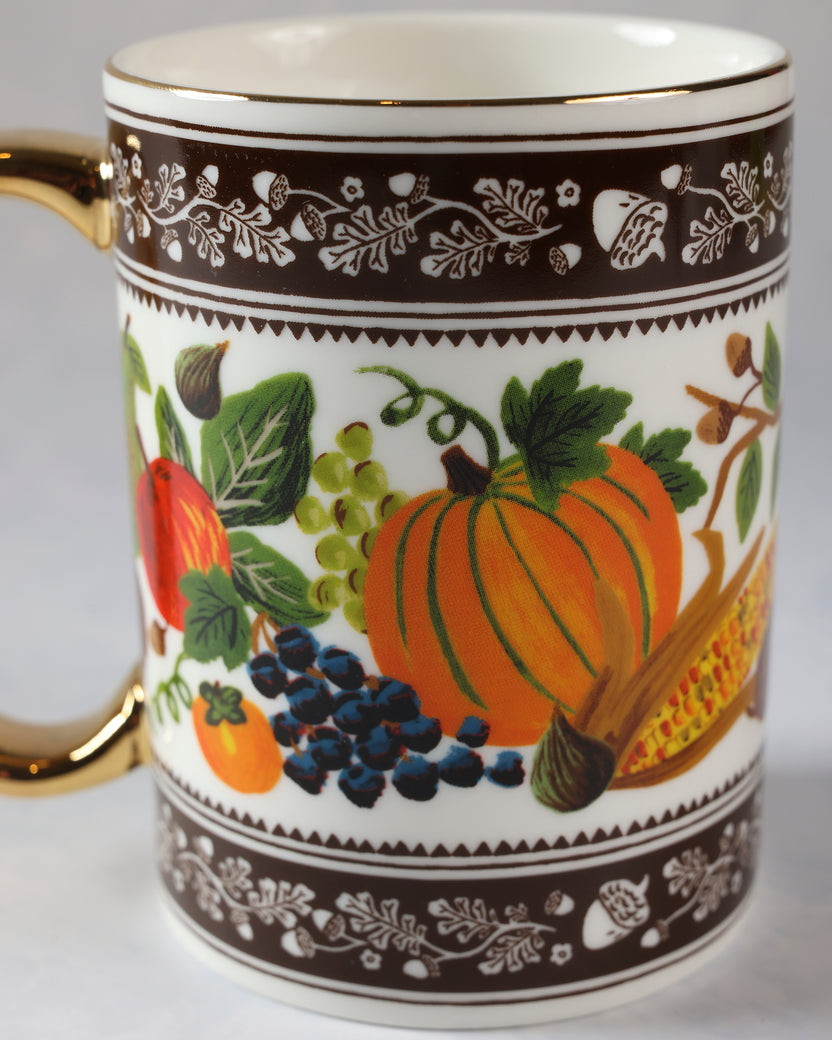 Close view of the harvest mug showing an orange pumpkin, grapes, berries, corn, and brown botanical borders.