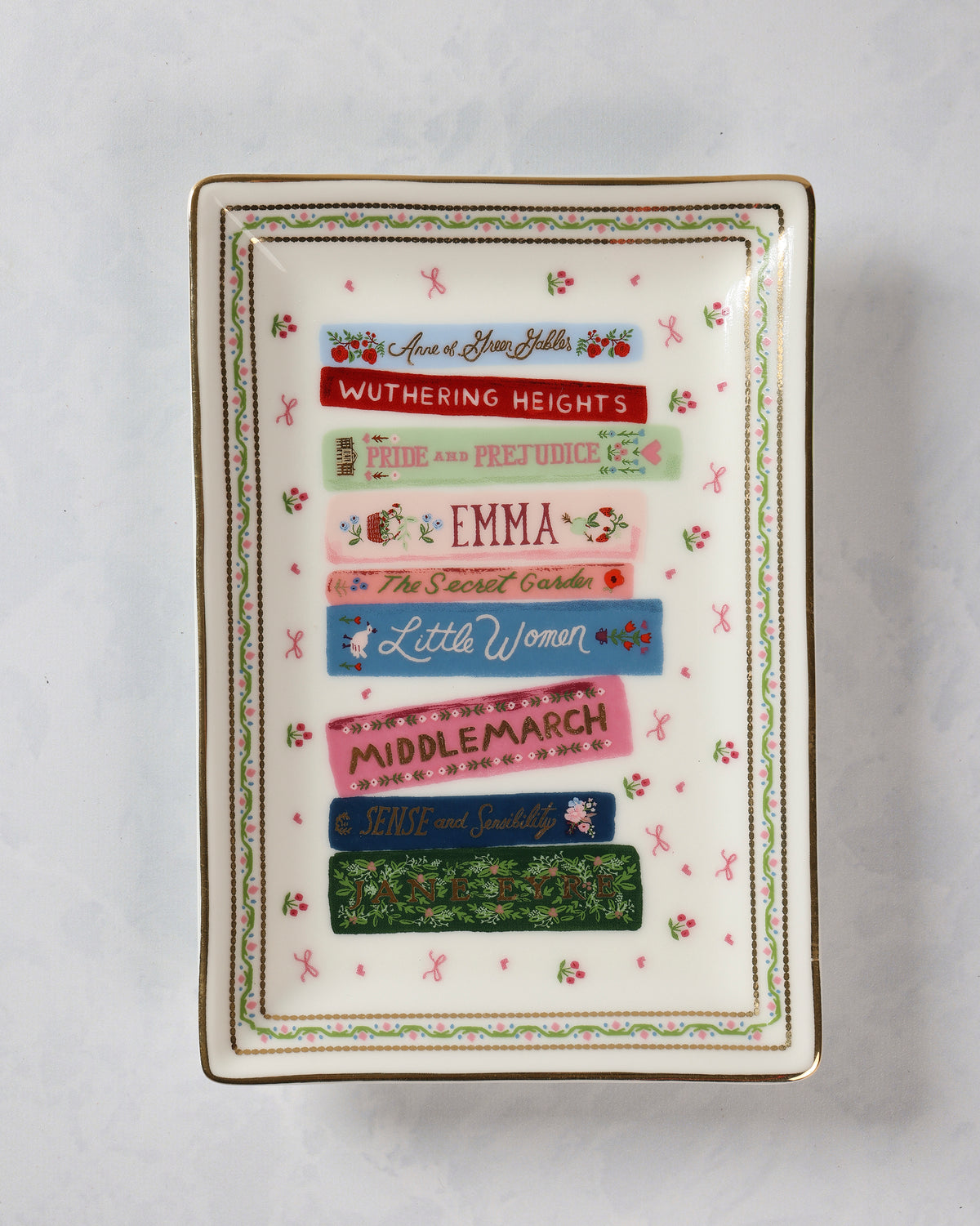 Rectangular porcelain catchall tray decorated with colorful book spines, including Anne of Green Gables, Wuthering Heights, Pride and Prejudice, Emma, The Secret Garden, Little Women, Middlemarch, Sense and Sensibility, and Jane Eyre.
