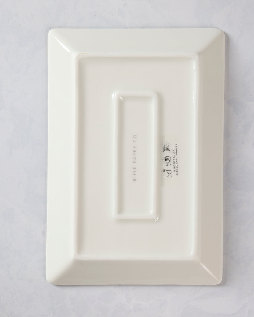 Back of a rectangular porcelain catchall tray with raised rectangular sections and printed Rifle Paper Co. markings.