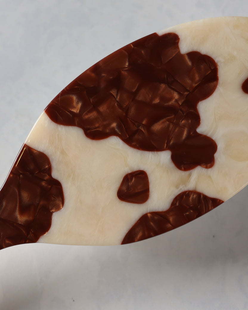 Close-up of the brown-and-cream hand-painted cowhide pattern on a hair brush.