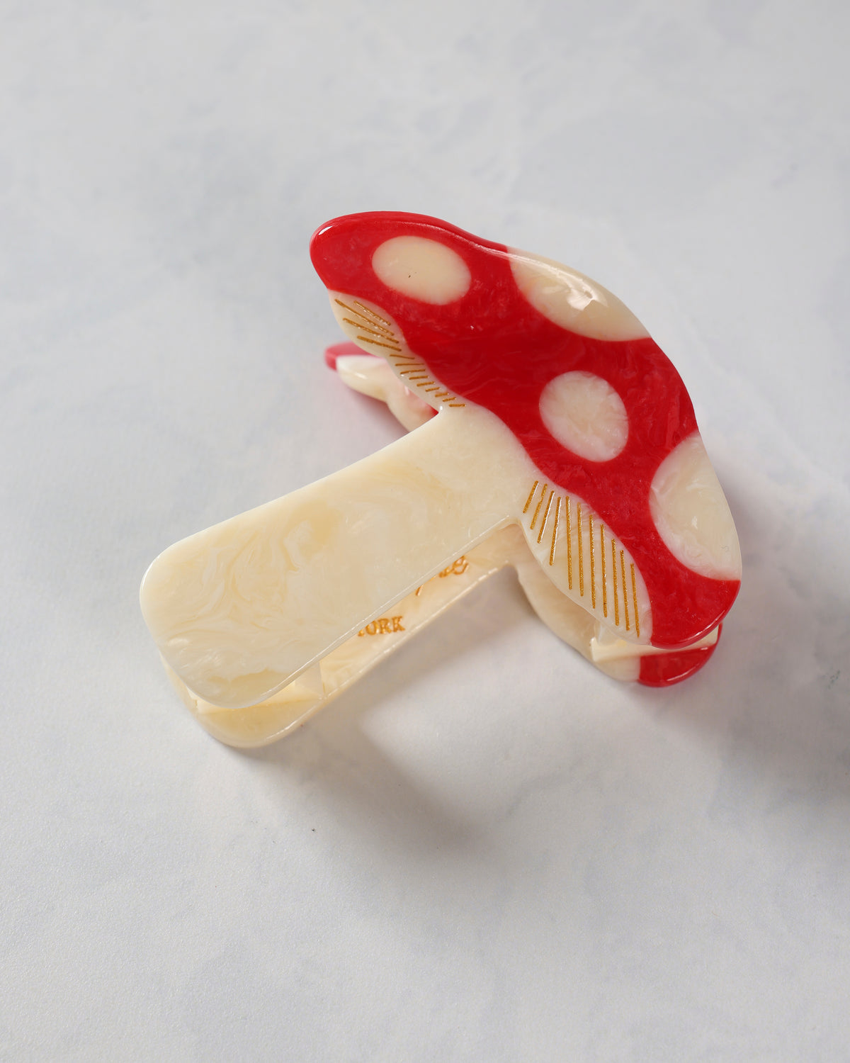 Red-and-cream mushroom-pattern claw hair clip shown closed from an angled view.