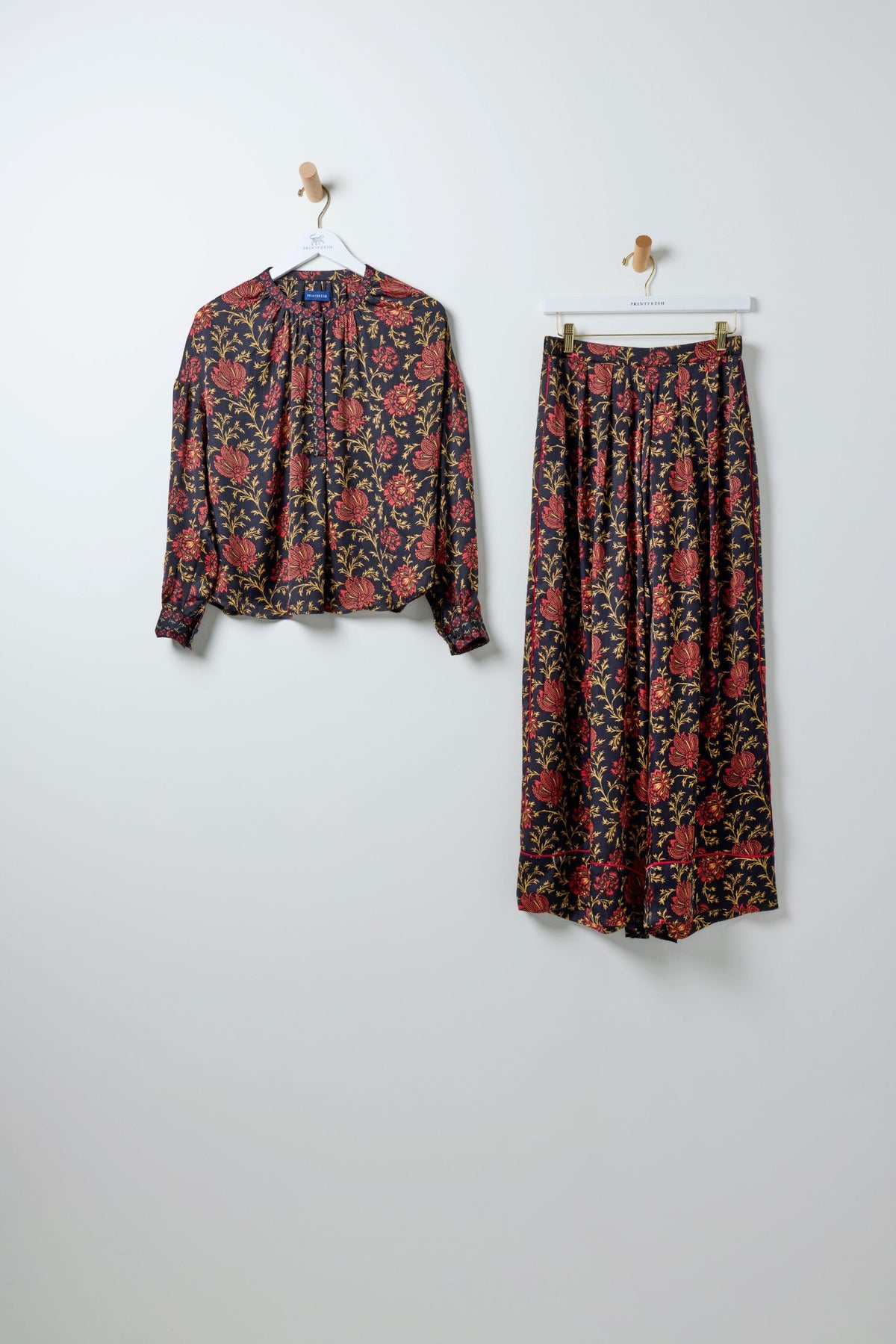 Drew blouse and Sasha pants hanging side by side, both in the Midwinter Bloom floral print.