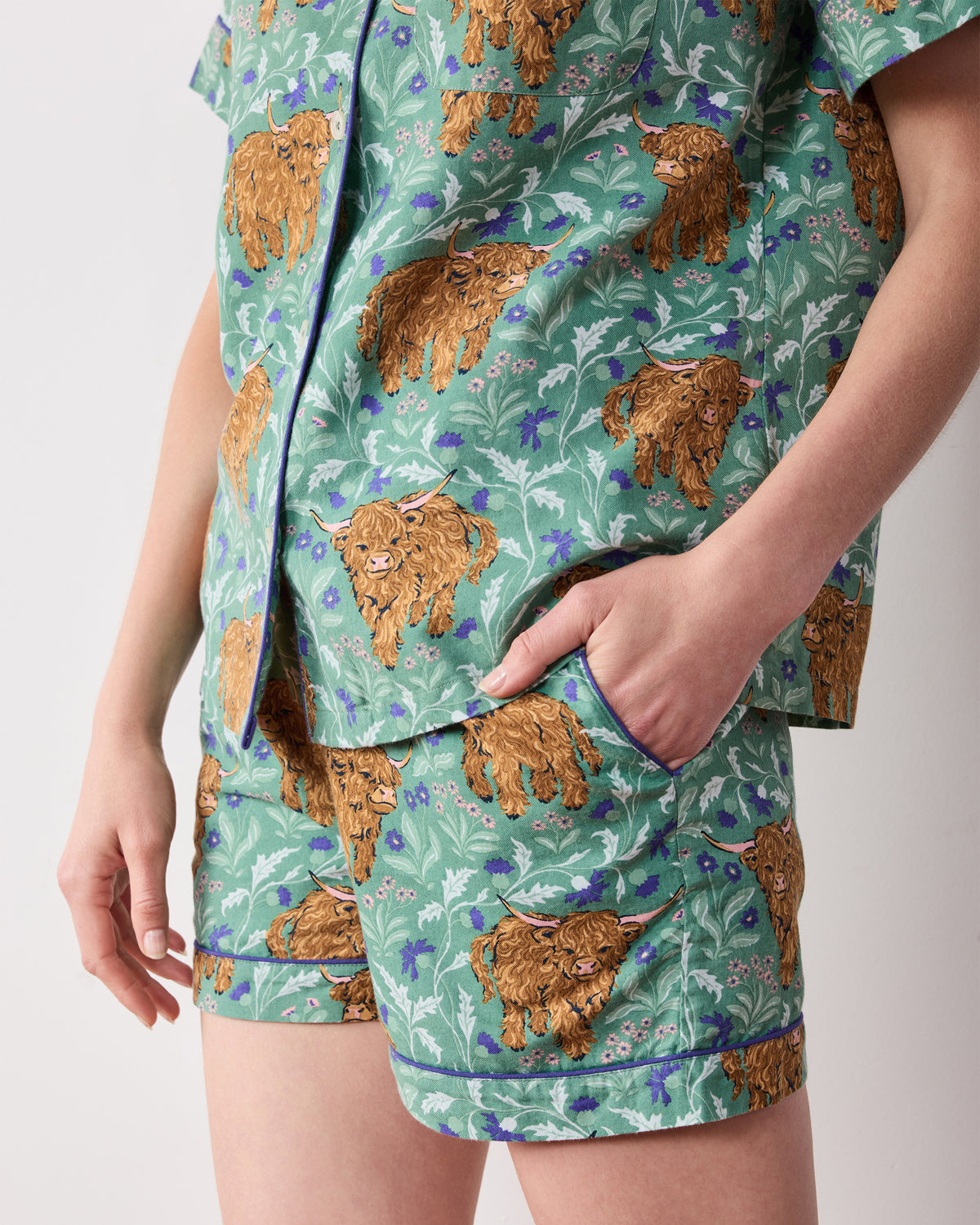 Close view of the Soft Thistle Highland Cows pajama shorts and top, showing the shorts pocket and contrast piping.