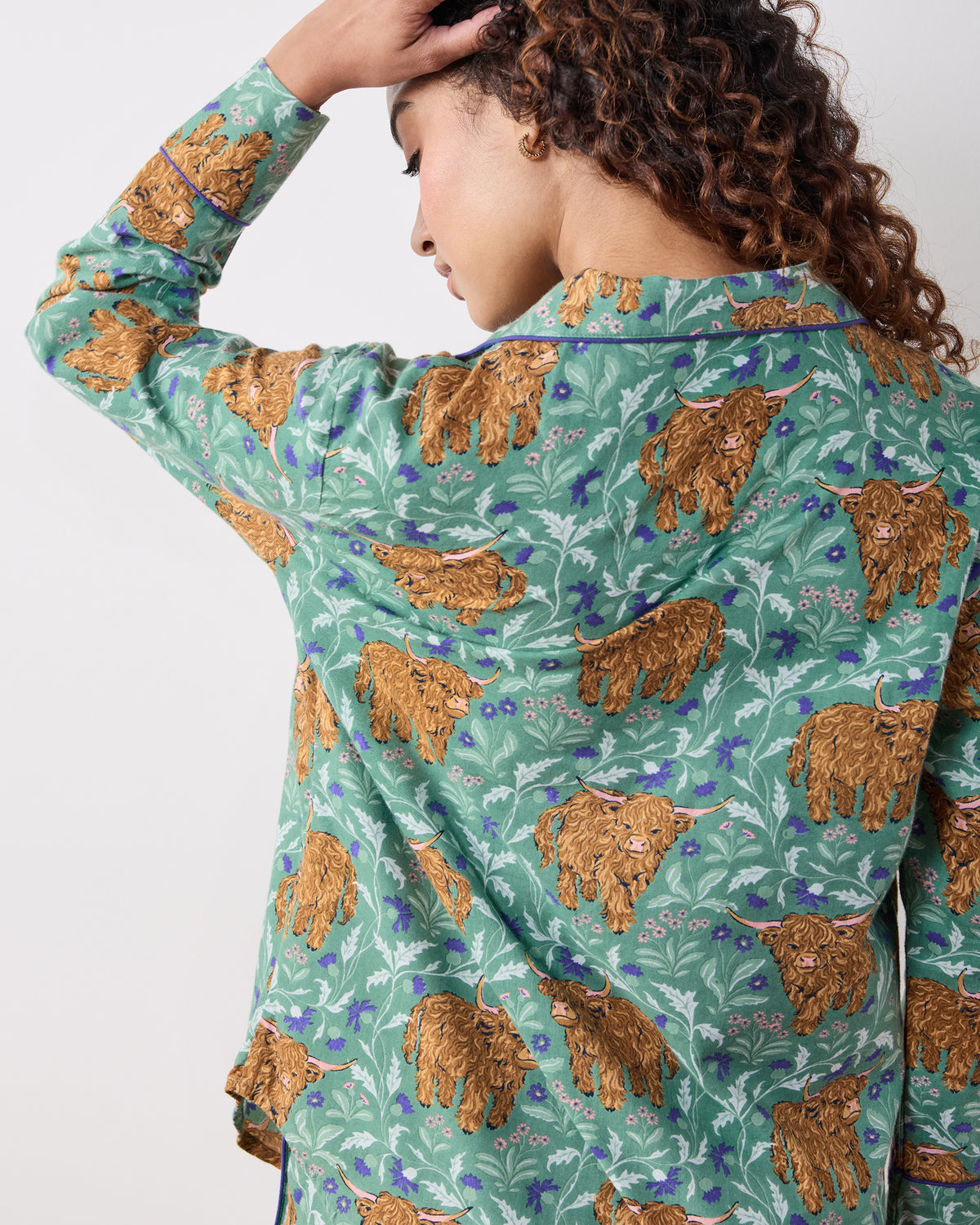 Close-up back view of the green Highland Cows pajama top, showing the collar, long sleeve, and printed brown cows among flowers.