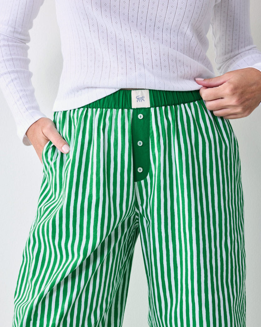 Close-up of the striped pajama pants showing the elastic waistband, button placket, side pocket, and inner label.