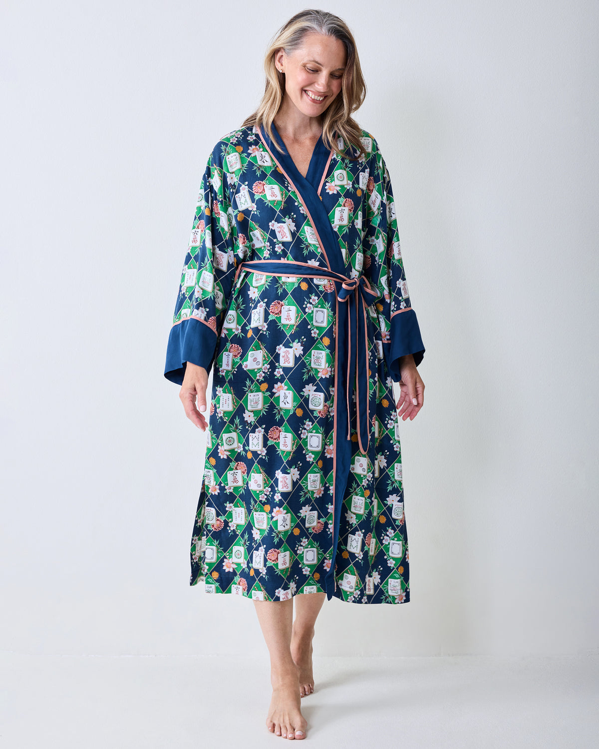 Full-length front view of the wintergreen Mahj Garden robe with dark blue trim, pink waist ties, wide cuffs, and floral patterned labels.