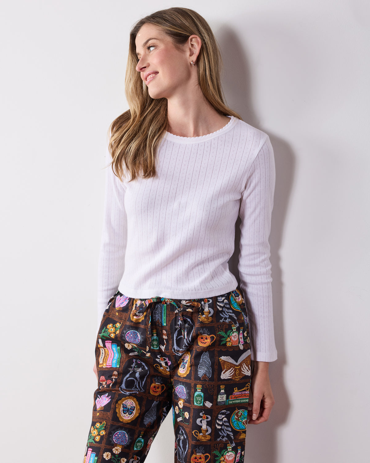 Front view of the Enchanted Study petite pajama pants, showing the elastic drawstring waist, side pockets, and illustrated cabinet-of-curiosities print.