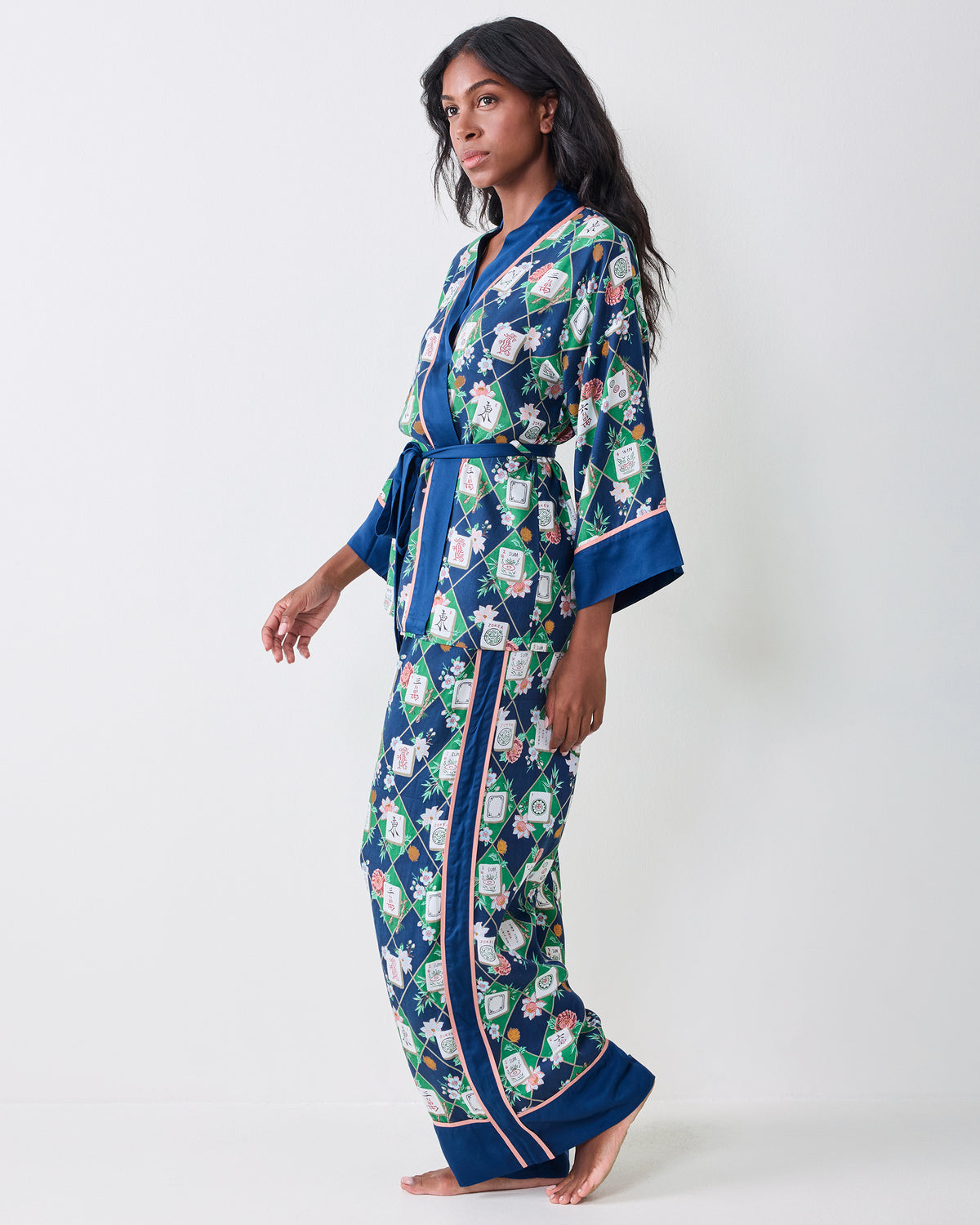 Three-quarter front view of the Mahj Garden Eco Satin Wrap Set in Wintergreen, showing the wrap top, blue contrast trim, waist tie, and matching wide-leg pants.