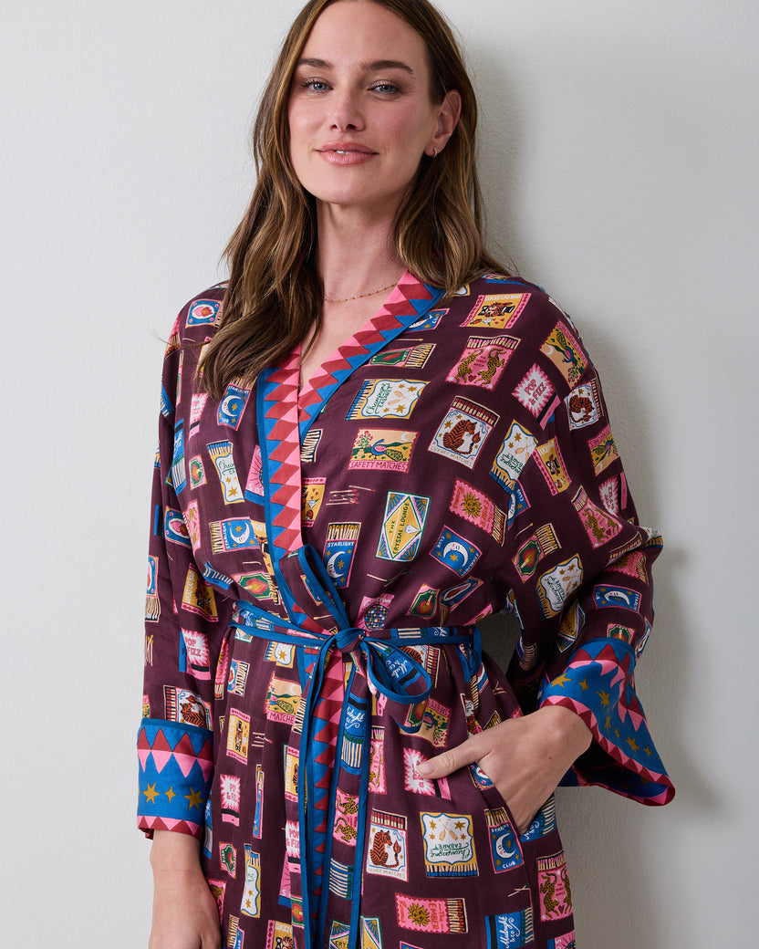 Upper front view of the Cabernet Painted Matchbook robe, showing the wrap collar, tied belt, pocket, patterned fabric, and contrasting cuff trim.