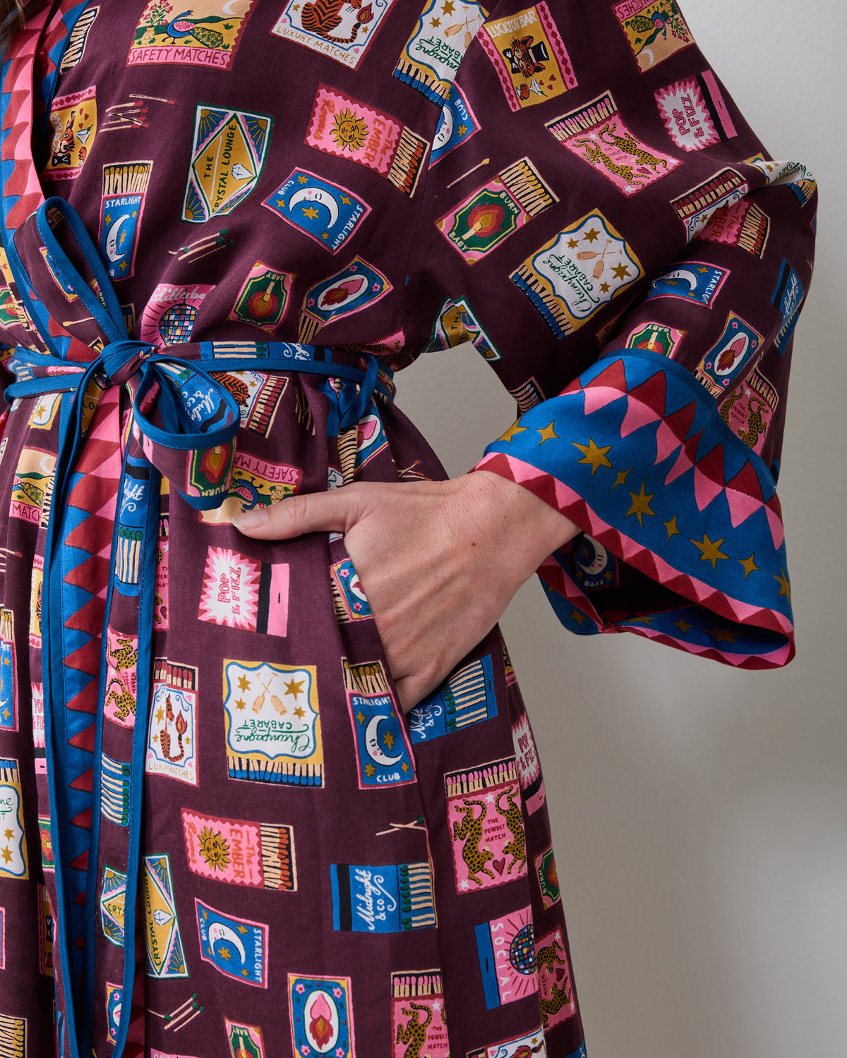 Close-up front view of the Cabernet Painted Matchbook robe, showing its matching belt, pocket, patterned sleeves, and contrasting blue-and-pink cuffs.