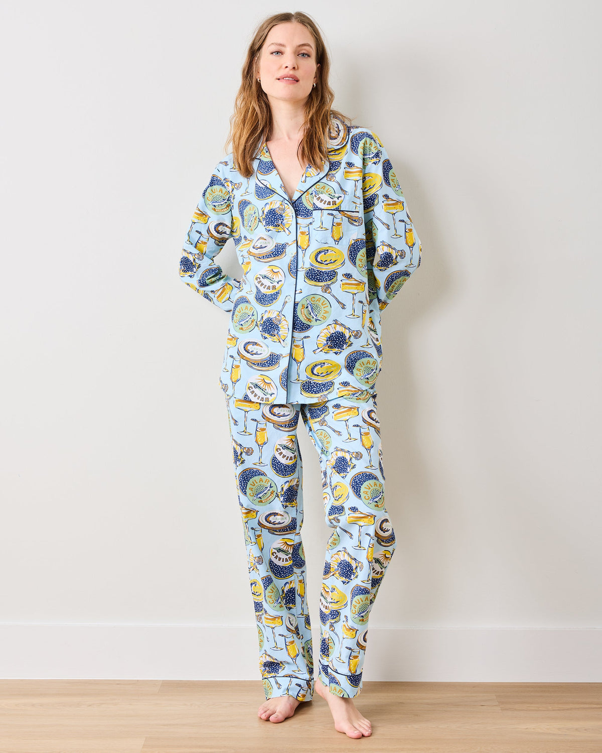 Model wearing the full pale-blue Champagne and Caviar long pajama set with a button-down top and matching pants.