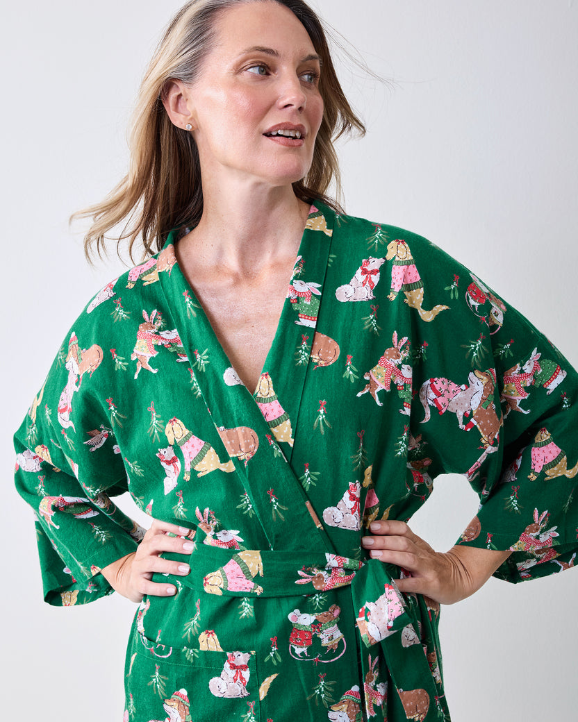 Person wearing the green Mistletoe Kiss long robe with a matching belt, long sleeves, and festive animal print.