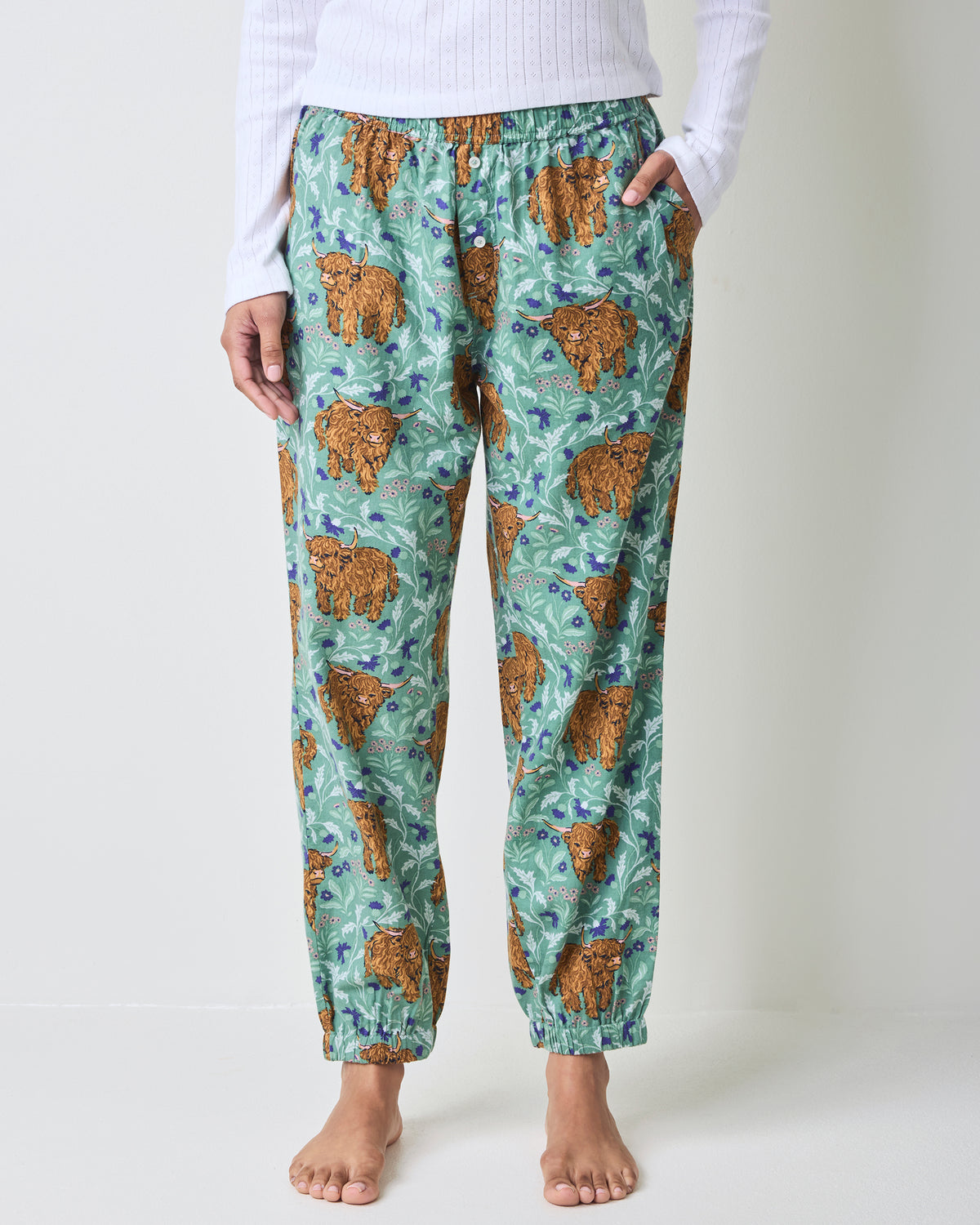 Front view of green Highland cow-print joggers with elastic waistband, pockets, and ankle cuffs