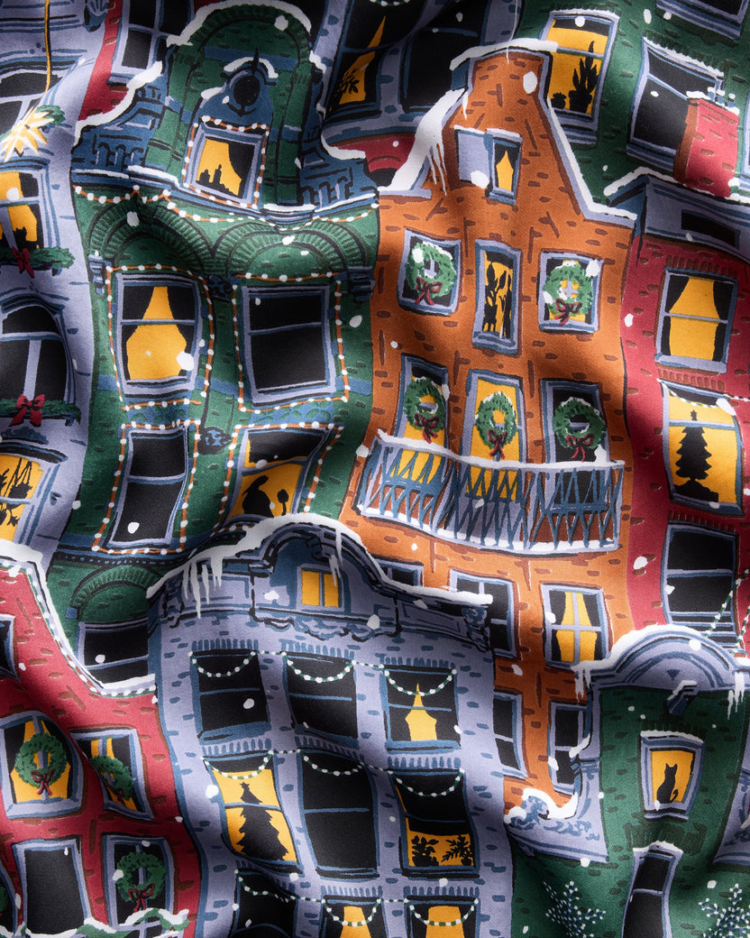 Close-up of the set’s colorful Christmas brownstone-building print, showing decorated windows, wreaths, trees, and snow.