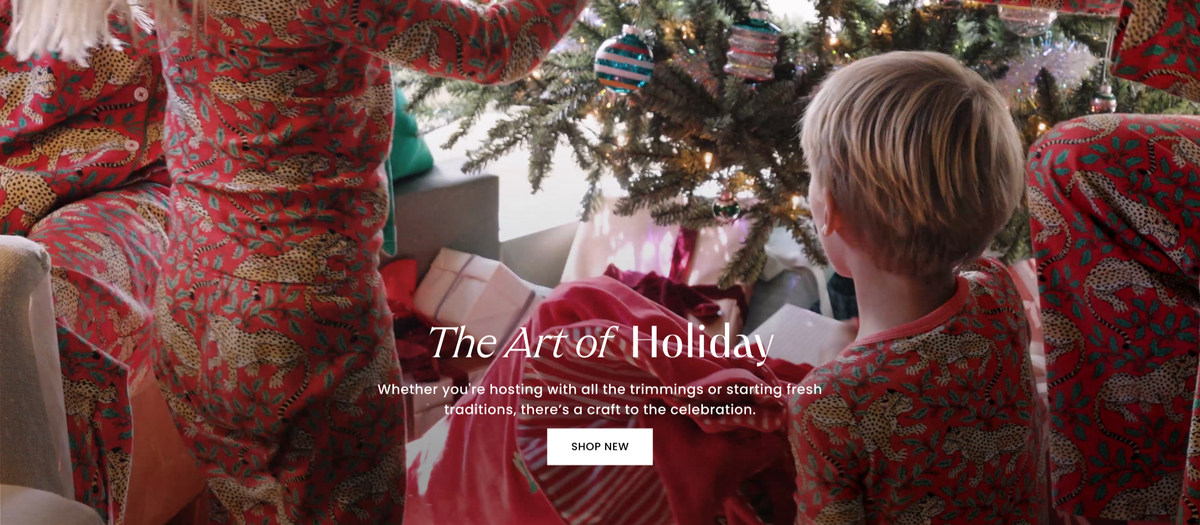 People in patterned red clothing gather around a lit Christmas tree; text reads “The Art of Holiday” and “Whether you're hosting with all the trimmings or starting fresh traditions, there's a craft to the celebration.” with a “SHOP NEW” button.