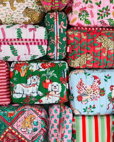 Several colorful patterned zippered pouches arranged together, including designs with dogs, leopards, flowers, holiday greenery, and vertical stripes.