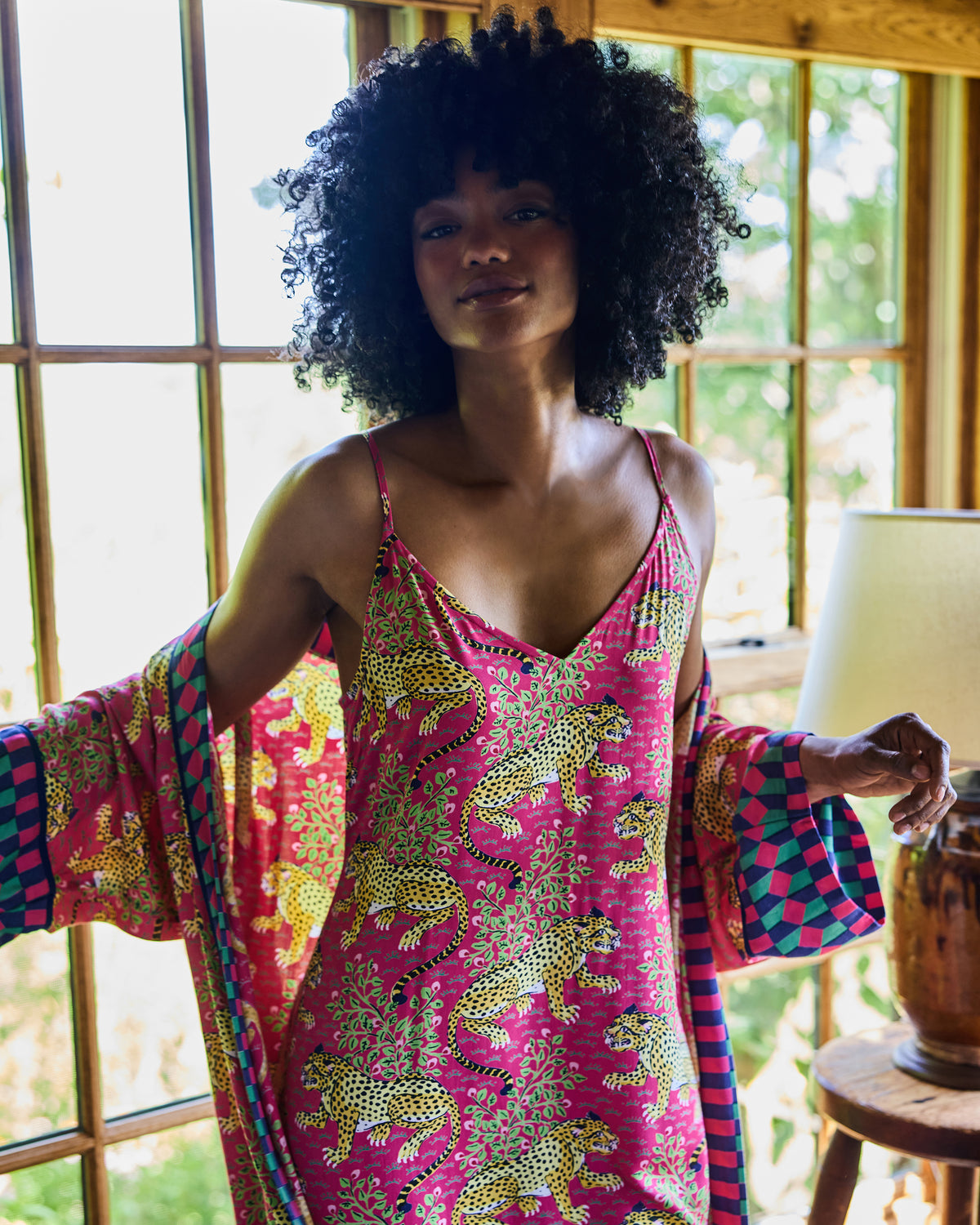 Person wearing a hot pink leopard-print nightie with a matching geometric-print robe draped over the arms