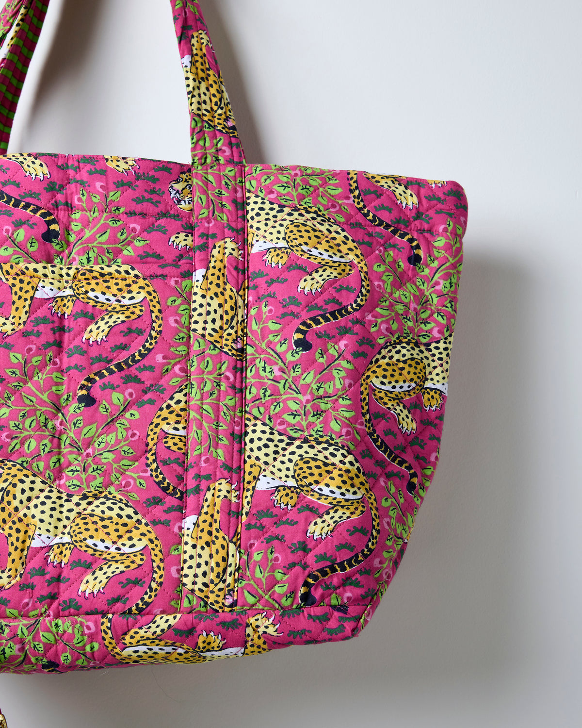 Close-up of the hot pink Bagheera weekend bag showing its leopard-and-leaf print and quilted construction.