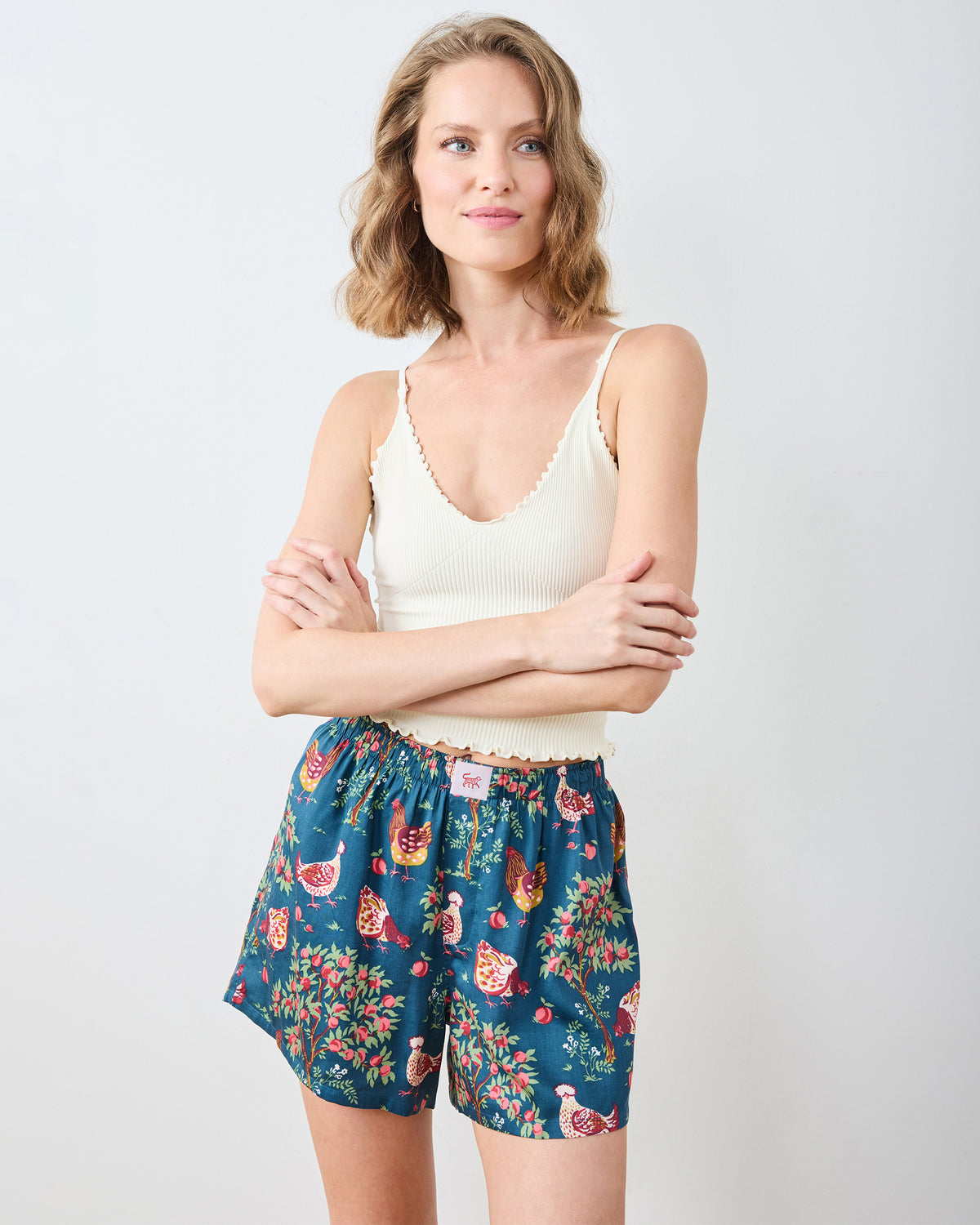 Model wearing navy Hen House boyfriend boxers with a chicken-and-floral print, shown from the front.