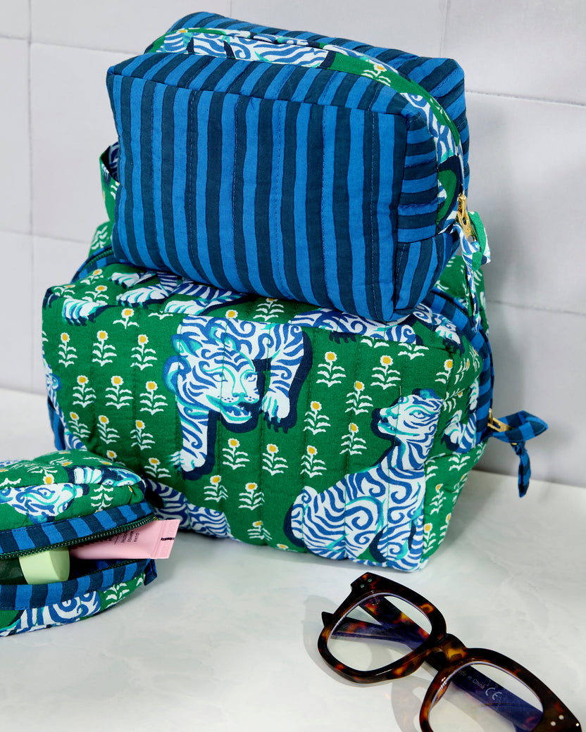 Three quilted pouches in jade and blue, stacked together; the large and small pouches have a tiger print and the medium pouch has blue stripes.