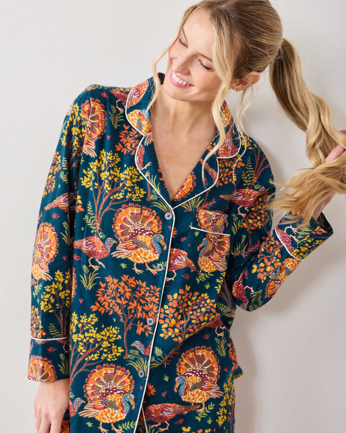 Model wearing the Turkey Trot navy pajama top with a turkey and autumn foliage print.